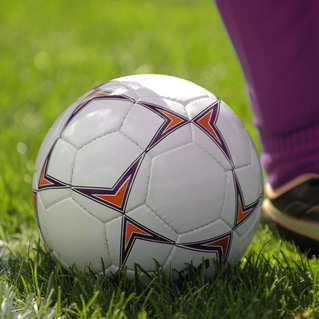 Soccer ball and persons leg showing purple sock